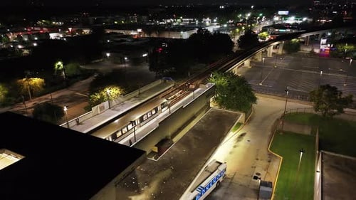 Luftaufnahme eines Zuges, der nachts die U-Bahnstation verlässt. Beleuchteter Bahnsteig an erhöhter Gleisanlage