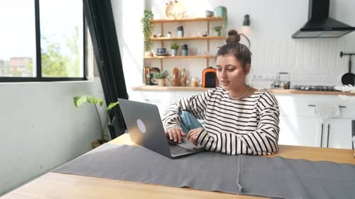 Woman Working on Laptop at Kitchen Table