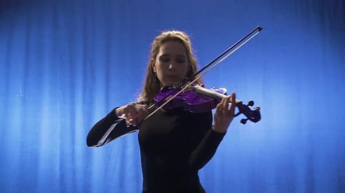 Woman plays violin in front of blue background