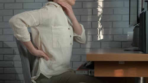Adult Massaging Neck and Lower Back at Computer