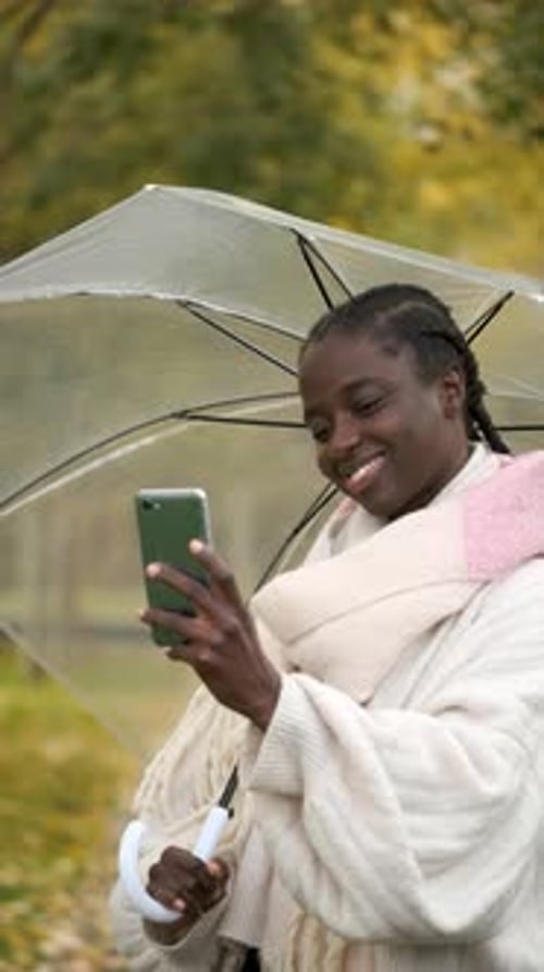 Woman with Umbrella Using Phone in Fall Setting