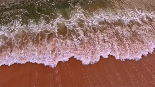 View From Air Shows Ocean Waves Crashing on Sandy Shores