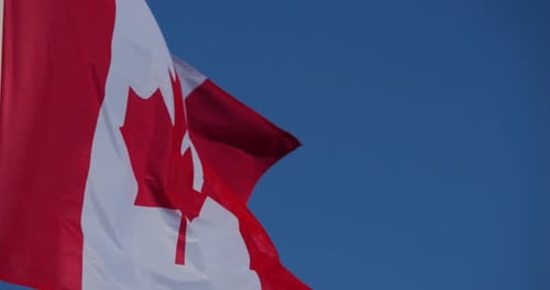 Canadian Flag Waving Against Blue Sky