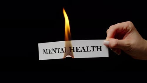 Female Hands Keeping Burning Paper with Phrase Mental Health