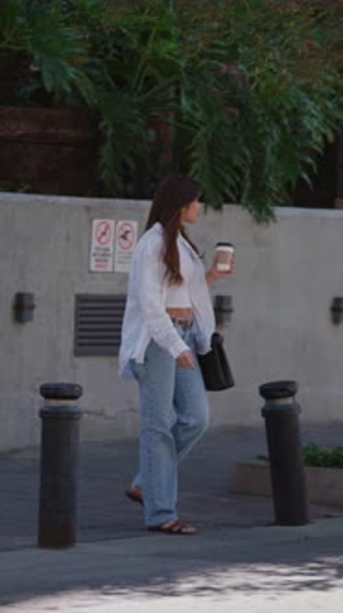Stylish Woman with Coffee Walks on City Street