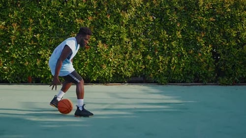 Sportive African American Man is Playing Basketball on Open Street Court Dribbling Throwing Ball