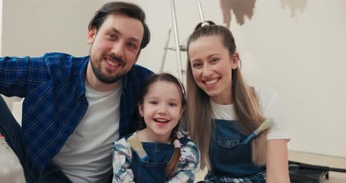 Smiling Family Painting Wall in Home Interior