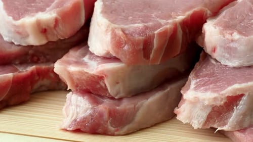Fresh Raw Pork Chops Stacked on Wood Surface