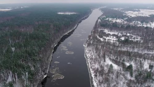 Aerial View of a Winter River Flowing Through a Snowcovered Forest Landscape