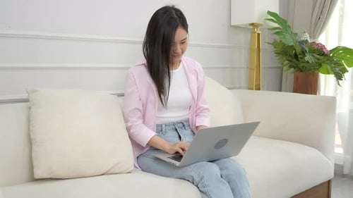 Young Woman Using Laptop on Sofa at Home