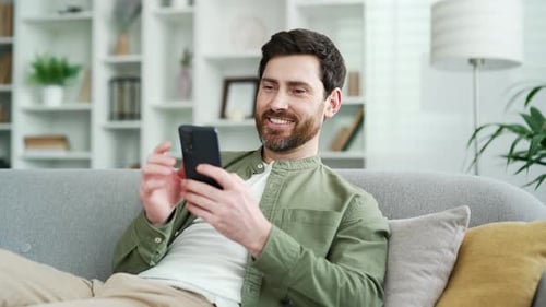 Man Relaxes on Couch Using Mobile Phone