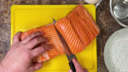 Cutting salmon fish with a knife for further cooking, preparing the fillet and removing the bones.