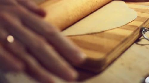 Hands Flattening Dough with a Rolling Pin