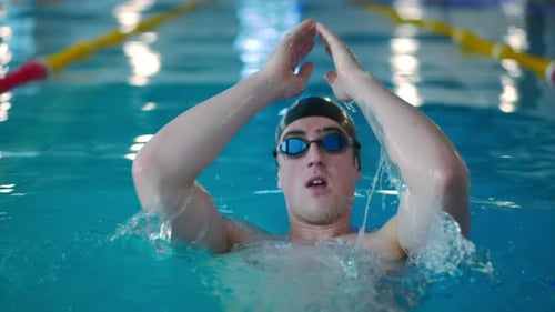Portrait of Young Sportsman Swimming on Back in Swimming Pool Track Indoors