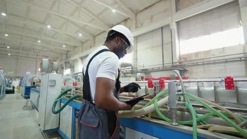 African Engineer in Uniform with Tablet Checks the Cooling System at the Factory