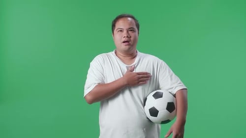 Asian Man With A Ball Singing National Anthem While Cheering Soccer On Green Screen Background