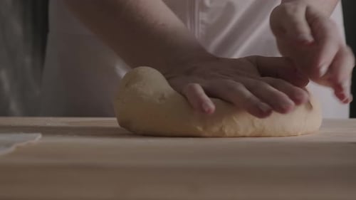 Baker Kneading Dough on Wooden Board