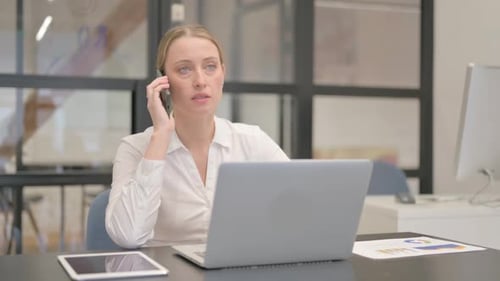 Woman Talking on Phone While Using Laptop