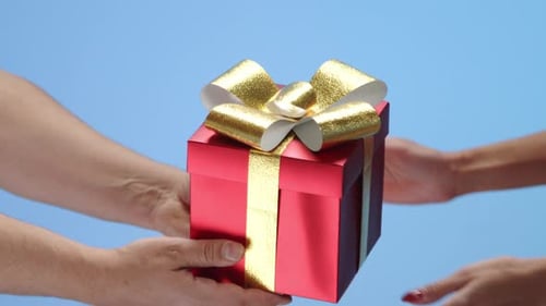 Close Up of Male Hands Holding Out Red Giftwrapped Square Box to Female Hands