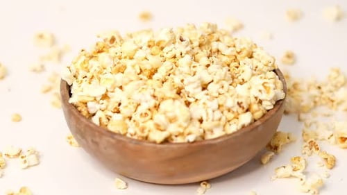 Popcorn Tossed in a Wooden Bowl on a White Background Slow Motion Video Female Hand Takes Popcorn