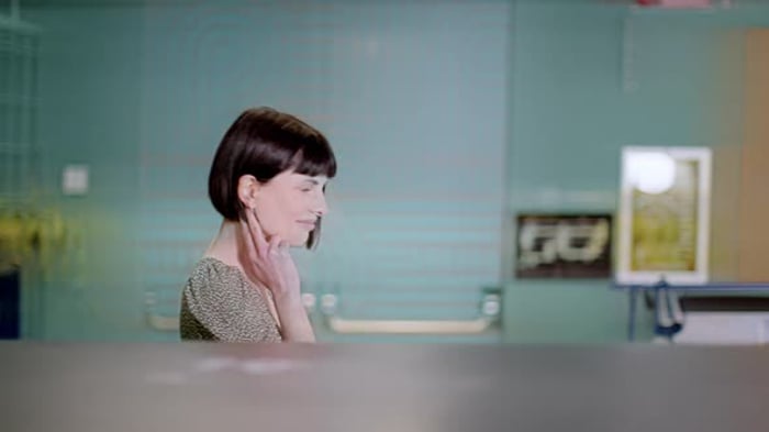 Businesswoman walking through office looking at camera, Business ...