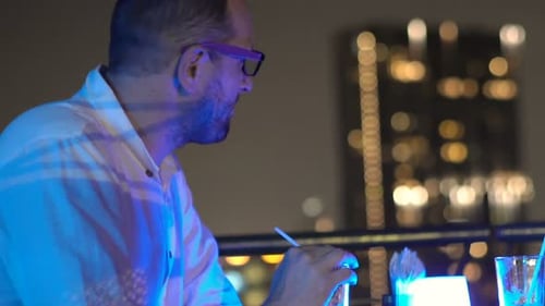 Young, Happy Man Drinking Cocktail Sitting on Terrace in Bar at Night Alcohol