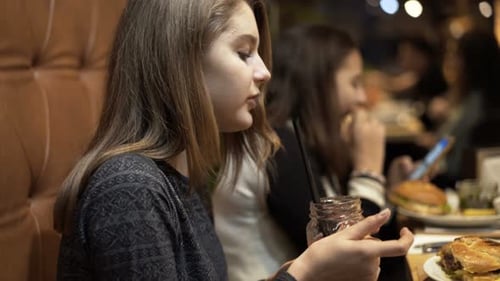Teenage Girl Drinking Juice And Eating French Fries In Cafe