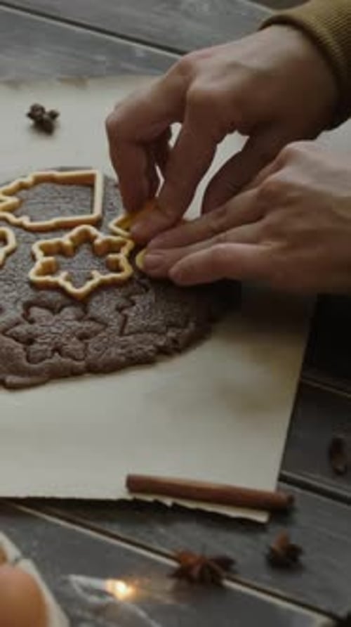Person Making Festive Cookies at Wooden Table