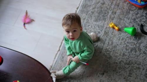 Adorable baby boy sitting on the floor looking up with surprise.