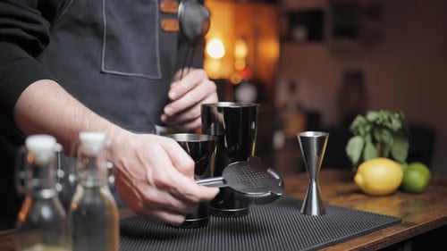 Slow-motion of bartender showing his strainer presenting bar equimpent. Perfect for mixology tutoria