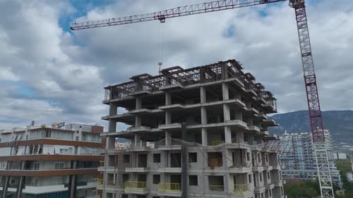 Vídeo aéreo del esqueleto de un edificio con una grúa torre visible