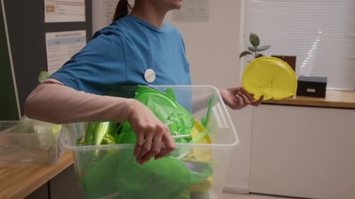 Voluntario ecológico sostiene un contenedor con residuos plásticos durante una presentación en la escuela