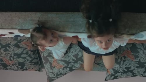 Two Young Girls Kneeling on Sofa from Above