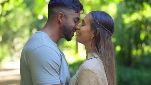 Happy young couple kissing in park for love, care and romance on anniversary date together