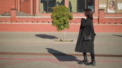 Sangle de sac à main ajustable pour dame passant devant un bâtiment en brique rouge