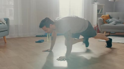 Strong Muscular Athletic Fit Man in T-shirt and Shorts is Doing Mountain Climber Exercises at Home