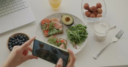 Smartphone photographing healthy food on table indoors