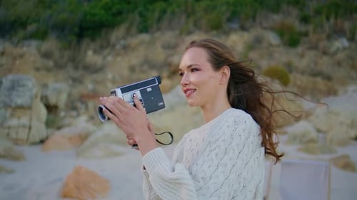 Woman Films with Vintage Camera on Beach