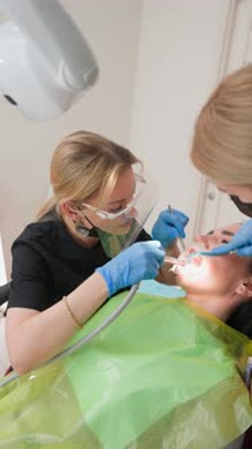 Woman with Braces is Examined in Clinic By Female Dentist and an Assistant