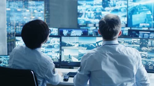 In the Security Control Room Two Officers Monitoring Multiple Screens for Suspicious Activities, Th