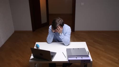 Stressed Office Worker Covering Face at Desk