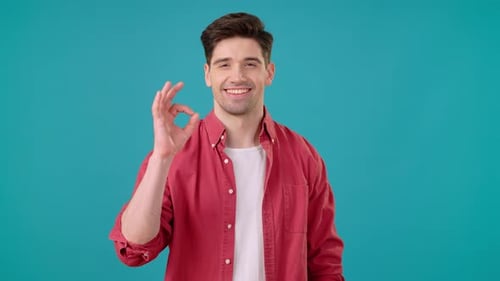 Smiling Man Gives Ok Hand Sign on Blue