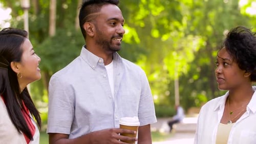Happy multiethnic friends enjoy coffee and conversation in a sunny park
