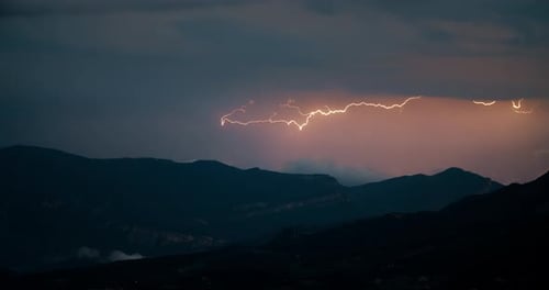 Epic Mountain Sunset Landscape with Thunderstorm Lightning on Sky at Horizon