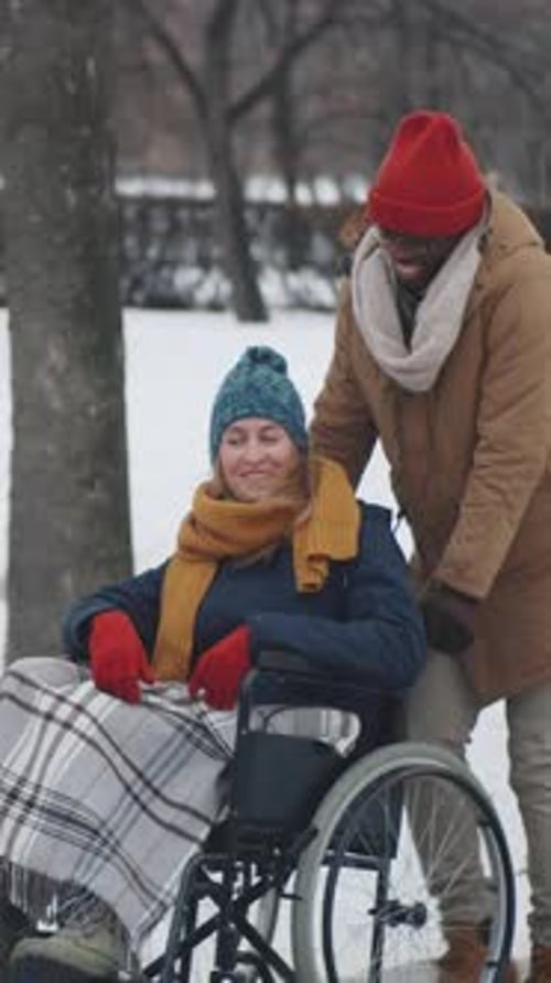 African American Man Assisting Female Friend during Walk on Winter Day