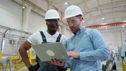 Supervisor and Manual Worker Using Laptop in Heavy Industry