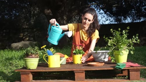 Woman Watering Newly Planted Potted Plants in Her Garden