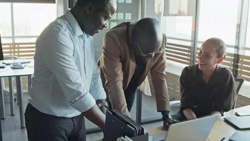 Coworkers Collaborate on Laptop in Modern Office