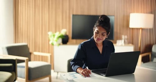 Woman Works With Laptop and Charts in Bright Room