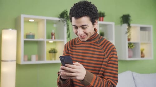 Smiling Young Adult Using Smartphone Indoors